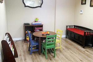 Children's play area with table and four chairs, bench, toy shelf, and magazine rack
