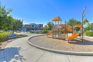 community playground, orange, soft ground, multiple slides, benches.
